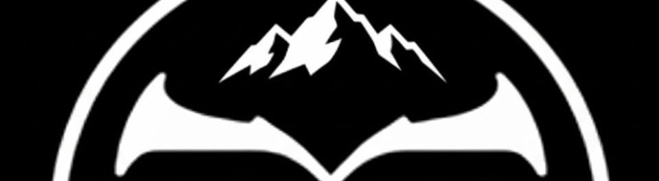 White logo on a black background featuring a stylized 'X' (crossed tools) inside a circle, with jagged mountain peaks rising above the center point.